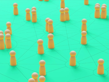 Yellow game pieces are arranged on a green surface connected by thin lines, illustrating a network or social connections. The pieces are grouped in small clusters, visually representing interconnected nodes in a network.